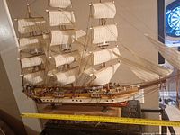 Full starboard side view of wooden clipper ship model showing sails, hull, measuring tape for size reference