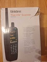 Front of retail box showing Uniden SDS100 branding and features, box corner wear visible