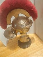 Helmet side view showing crest, cheek guard, neck guard and stand