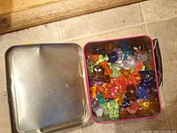 Open tin showing multicoloured Crazy Bones figures inside
