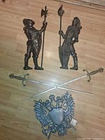 All five wall hangings laid out: two knight plaques, two swords, heraldic crest