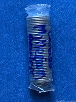 Sealed plastic-wrapped roll of coins with handwritten identification