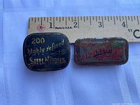 Front view of both tins beside ruler