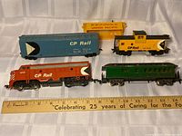 Five HO scale rail cars laid out beside ruler