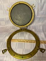 Porthole open showing mirror and hinge, ruler for scale