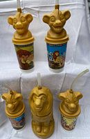 Five Lion King promotional cups, four with cub head lids, one full-body lion cup