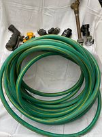 Coiled green hose with nozzle, valve pipe and assorted couplers
