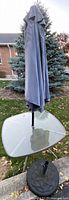 Glass top patio table with umbrella inserted and separate round base