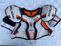 Bauer white, orange and black shoulder pads with "Bauer" branding on caps
