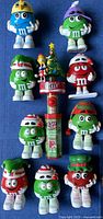 Front view of eleven assorted M&M’s holiday candy dispensers laid out on blue background