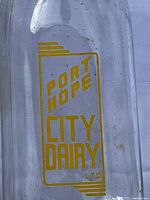 Close-up of yellow Port Hope City Dairy Ltd lettering on glass bottle