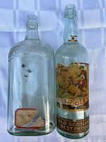 Front view of both whiskey bottles showing embossing and remaining label