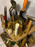 angled view of caddy showing screwdrivers, hammer, pliers, plumb bob and fasteners