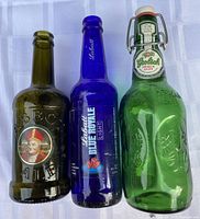 Three assorted coloured beer bottles standing side by side