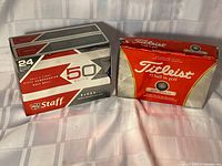 Wilson Staff 24-count box beside Titleist 12-count box