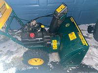 Full left side view showing engine, tire, auger housing and chute