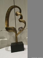 Front view of abstract gold-tone sculpture on base