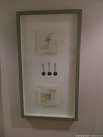 Full view of framed artwork showing two calligraphy squares and three coins