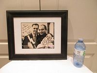 Front view of framed autographed photo with water bottle for scale