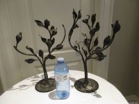 Two metal tree-form stands beside water bottle for scale