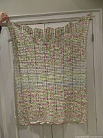Full view of crocheted throw hanging, showing size and colour pattern