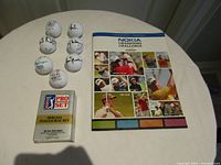 Lot overview showing autographed golf balls, event program and Pro Set tin