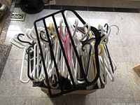 Box filled with white plastic tubular hangers and black multi-tier hanger