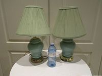 Front view of both lamps with shades and reference bottle for scale