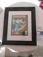 Full view of framed program next to water bottle for scale