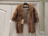 Front view of mink stole hanging on hanger showing fur texture and sleeve length