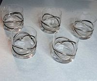 Five identical clear glasses with platinum swirl bands displayed top view