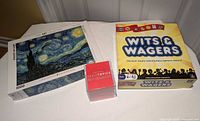 Front view of all three boxed items: Eurographics Starry Night puzzle, Wits & Wagers Family Edition game, TableTopics sealed card set