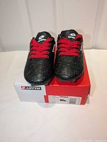 Front view of cleats on box showing uppers, laces, and brand logo