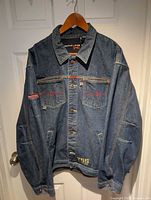 Front view of denim jacket showing button front, pockets, red stitching, T5S hem embroidery