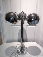 Front view entire lamp showing three chrome spherical heads and column base