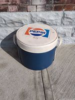 Full view of blue cooler with white Pepsi logo lid and handles