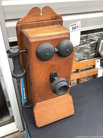 Front view of antique wooden wall phone showing receiver, bells and mouthpiece