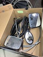 Box of assorted bicycle parts including mirrors, cables, spokes and handlebar pieces