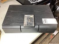 Overall view of black three-drawer cassette case with tape on top