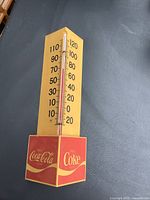 Front view showing entire thermometer, cube base with Coca-Cola logos, scale 10-120°