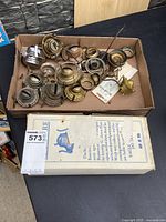 Tray with assortment of brass and metal lamp parts beside boxed Silex filter