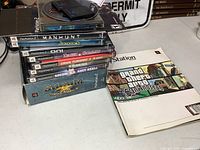 Stack of PlayStation 2 game cases, San Andreas guide, memory card atop