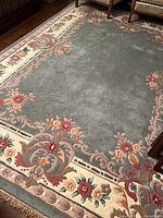 Full view of rug showing central field, floral border and fringe