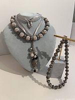 All three necklaces displayed; matinee with tassel on bust, one collar on bust, second collar draped over stand