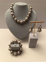 Full view of necklace, bracelet and earrings on display stands