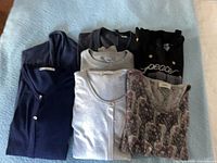 All seven folded tops laid out on surface