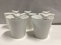 Five white ceramic flower pots with bird accents