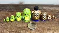 Full lineup of both frog and monkey nesting doll sets with quarter for scale