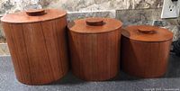 Front view of all three teak canisters with lids