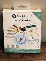Front of sealed retail box showing TrackR pixel device, smartphone illustration